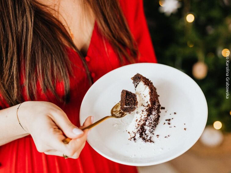 Mulher comendo um pedaço de bolo, alimento rico em açúcar.