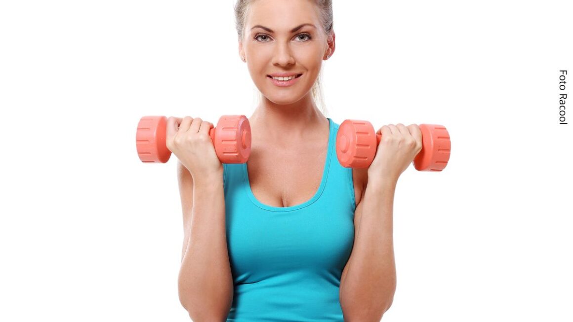 Mulher exibe músculos bíceps com dois halteres, um em cada mão.
