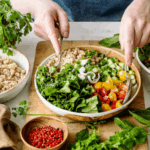 Close-up das mãos de uma mulher preparando uma receita à base de vegetais.