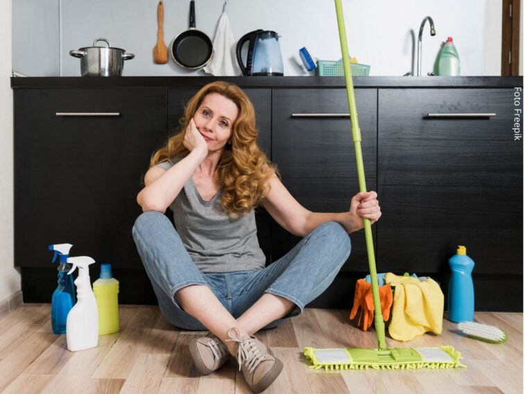 Vista frontal de mulher sentada no chão, segurando o esfregão com produtos de limpeza ao lado. Ideia de não divisão de tarefas domésticas