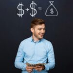 Foto de um homem jovem à frente de um quadro negro com cifrões desenhados. Conceito de economizar