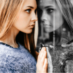 Close-up de jovem mulher de perfil, com expressão fechada, parada diante de uma vitrine de vidro refletindo seu rosto