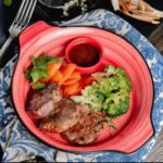 Close-up de um prato com carne grelhada, brócolis, feijão e vegetais, compondo a ideia de alimentos saudáveis.