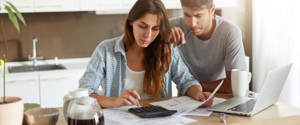 Foto de um casal jovem revisando suas contas bancárias e calculando os gastos