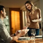 Imagem de casal jovem em casa à mesa se preparando para um jantar a dois