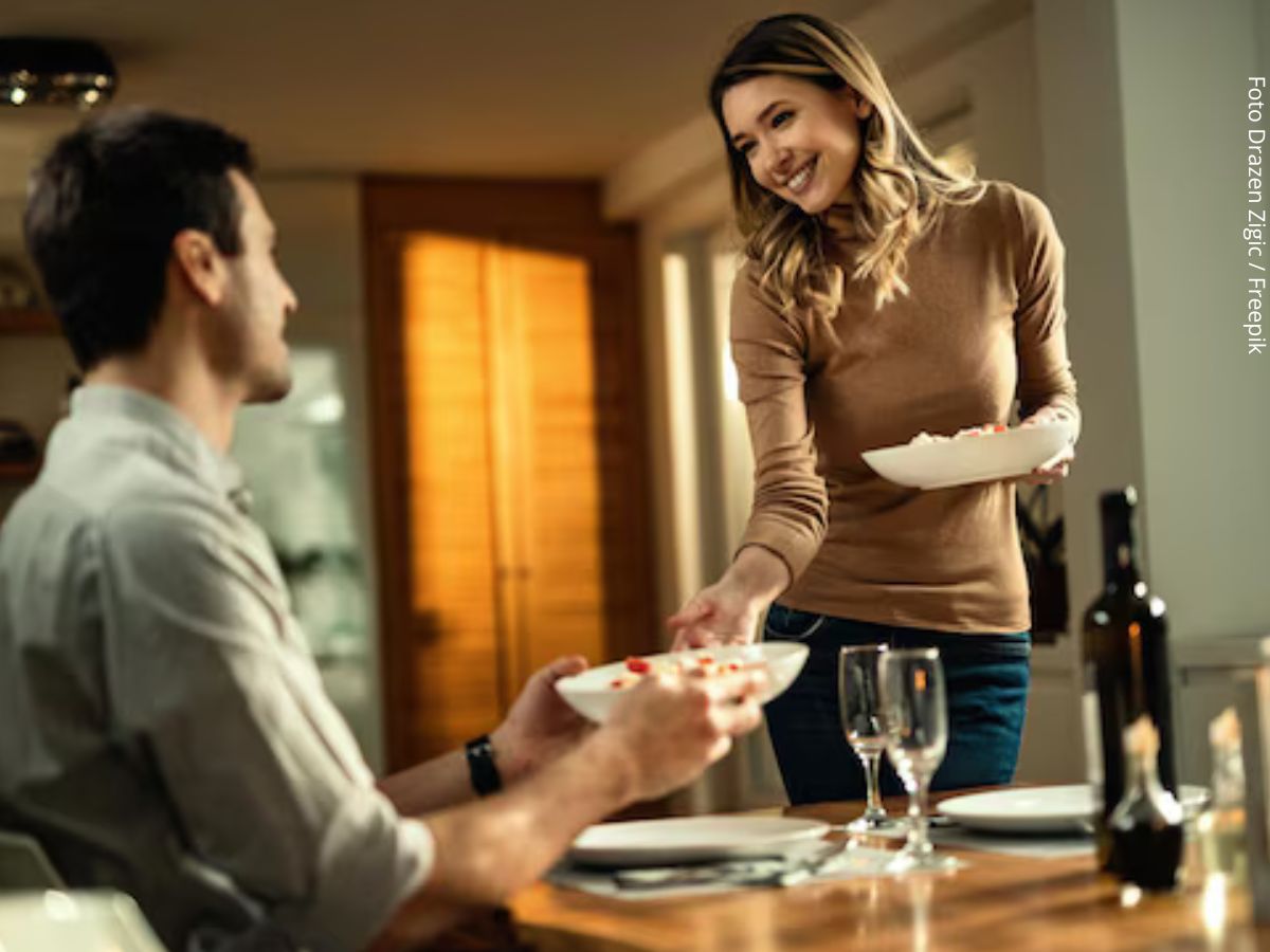 Imagem de casal jovem em casa à mesa se preparando para um jantar a dois