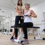 Imagem de uma mulher madura fazendo exercício de musculação sob a orientação de uma personal trainer em busca dos benefícios da musculação