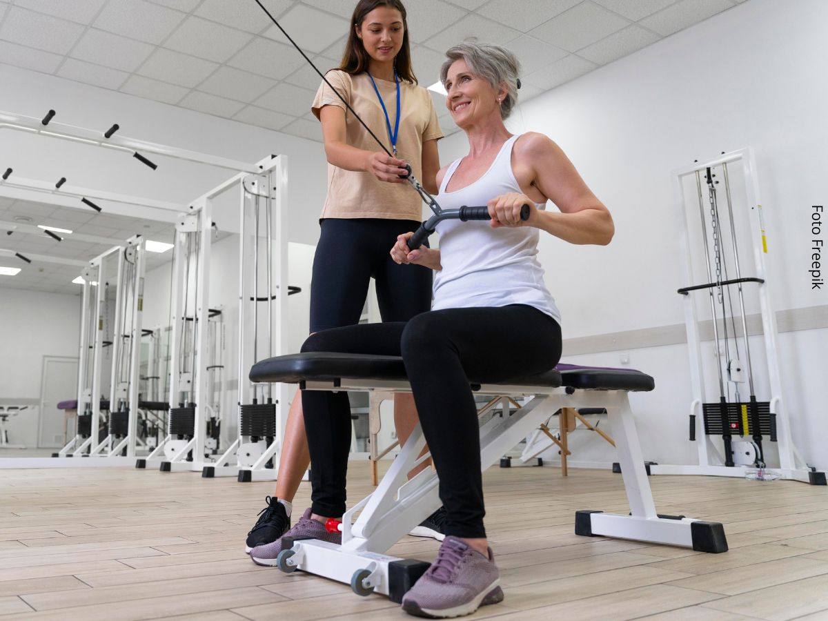 Imagem de uma mulher madura fazendo exercício de musculação sob a orientação de uma personal trainer em busca dos benefícios da musculação