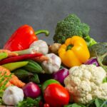 Imagem de uma composição de vegetais com berinjela, pimentões, tomate, brócolis, cebola cogumelos, simbolizando comida de verdade