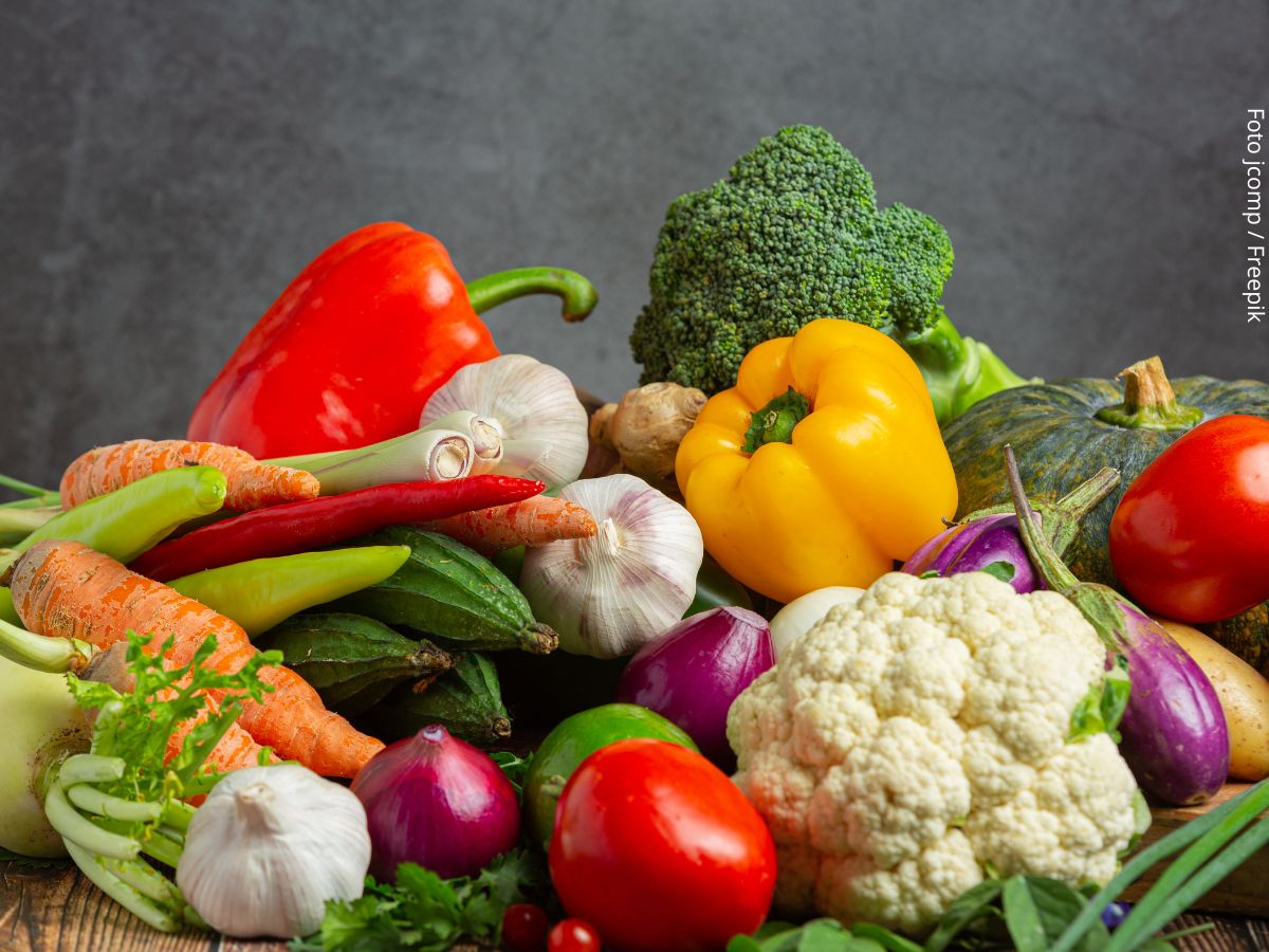 Imagem de uma composição de vegetais com berinjela, pimentões, tomate, brócolis, cebola cogumelos, simbolizando comida de verdade