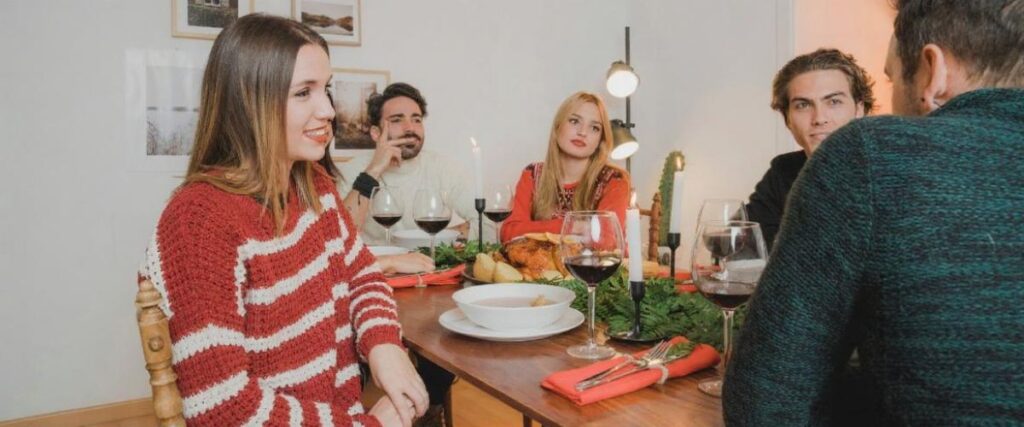 Imagem de um encontro de amigos amigos sentados à mesa jantando e conversando