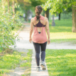 Imagem de uma mulher jovem branca andando em um parque, simbolizando uma caminhada meditativa.
