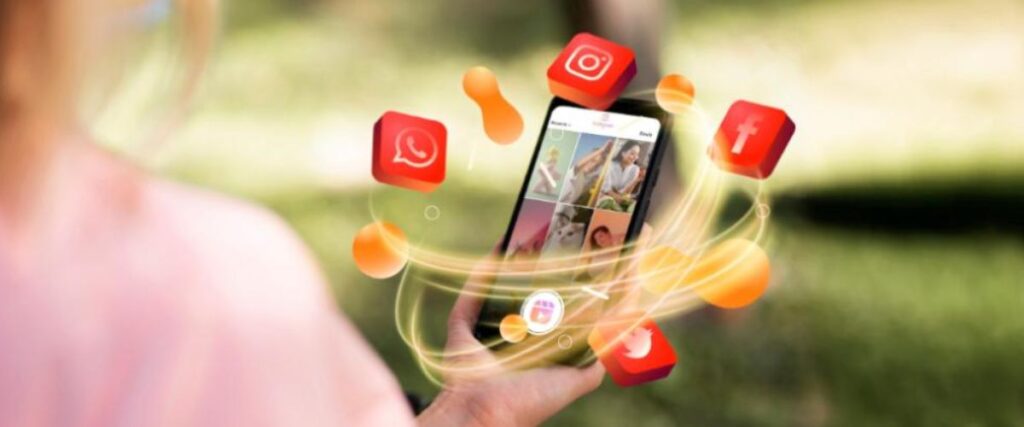Imagem conceitual de redes sociais, com imagens de símbolos de apps girando em torno de um celular segurado por uma mão