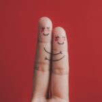 Imagem dos dedos indicador e do meio desenhados com rostos e se abraçando, sugerindo empatia emocional