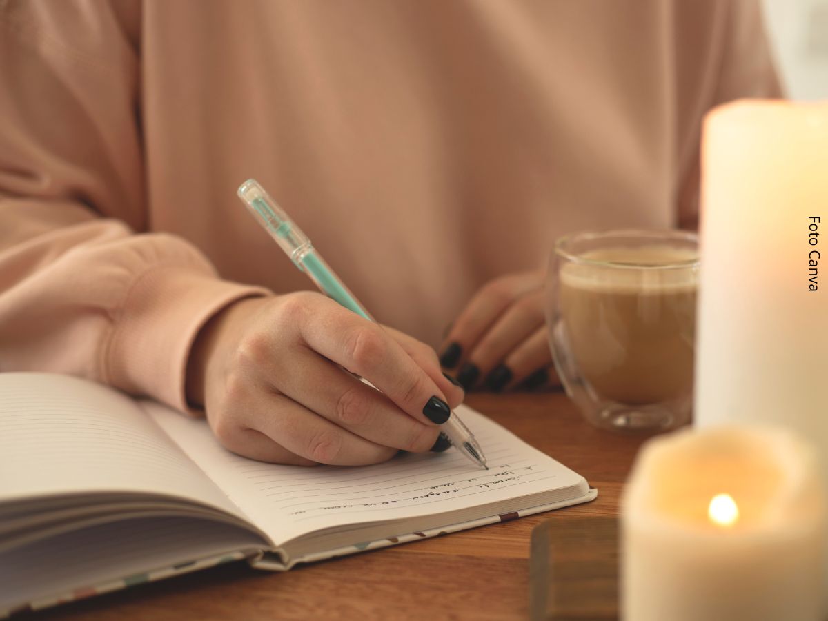 Close-up de uma mão feminina escrevendo em um caderno ou diário, simbolizando a ideia de ficar sozinho.
