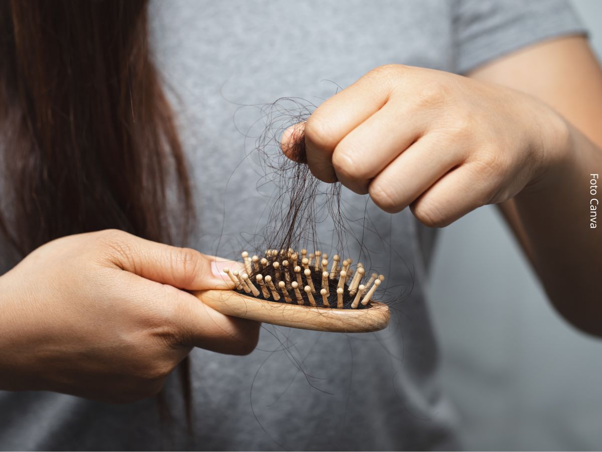 Imagem de uma mulher tirando chumaço de cabelo de uma escova após se pentear, simbolizando queda de cabelo