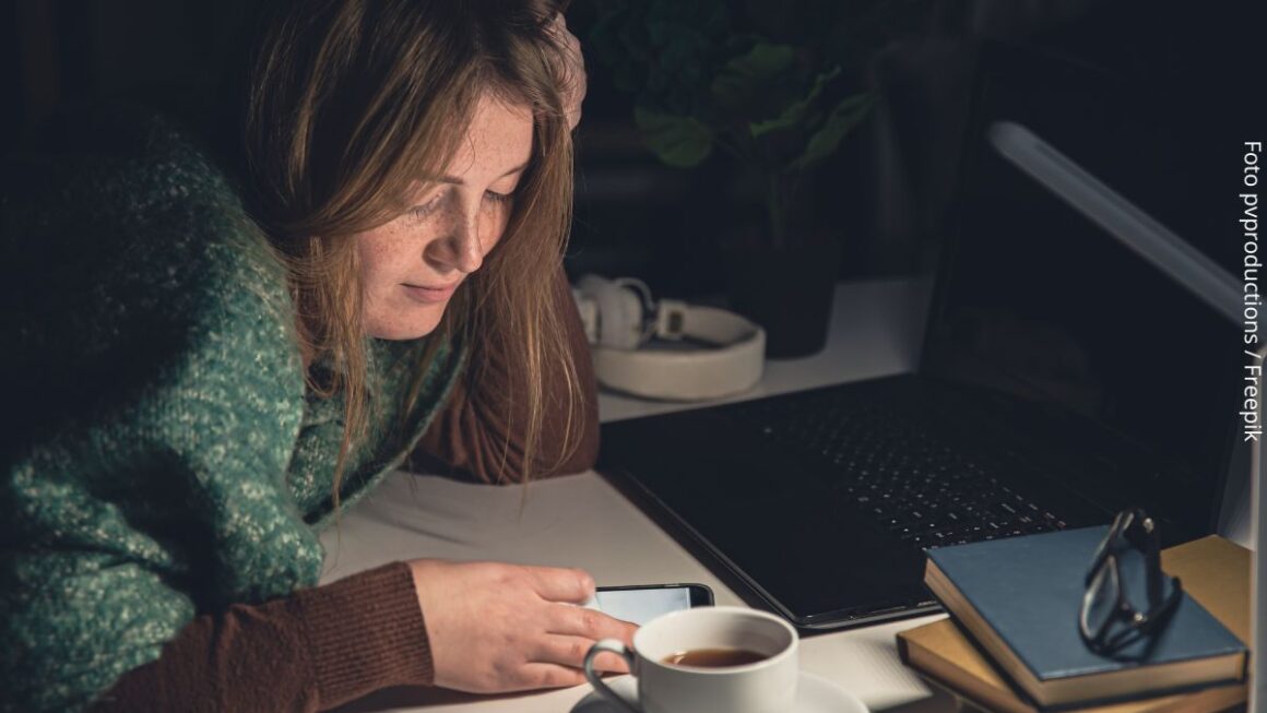 Imagem de uma mulher olhando o celular distraída, a repetir hábitos comuns da procrastinação.