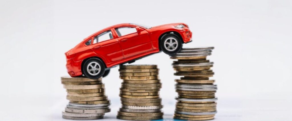 Imagem de carro de brinquedo vermelho sobre pilhas de moedas no sentido ascendente.